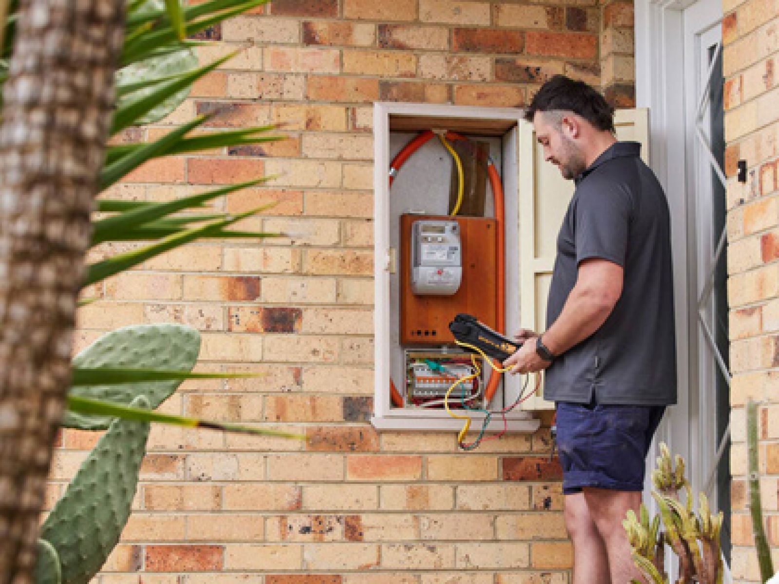 RACV Tradesman on house porch conducting electrical test in the powerbox.