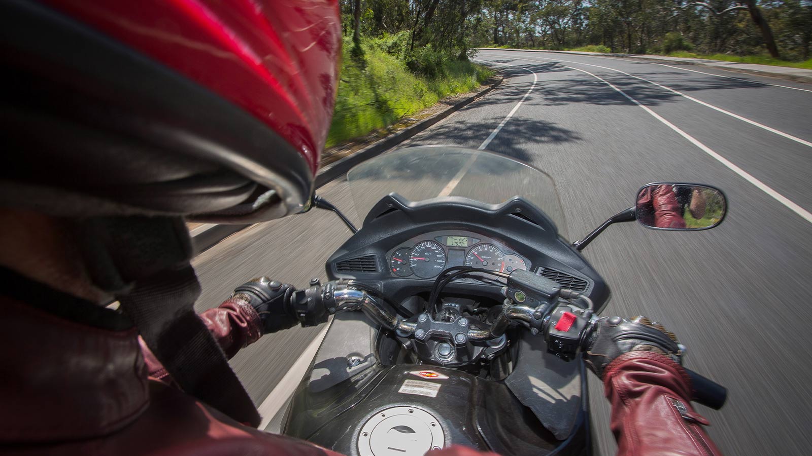 Close up of a motorcyclist riding while checking the speedometer.