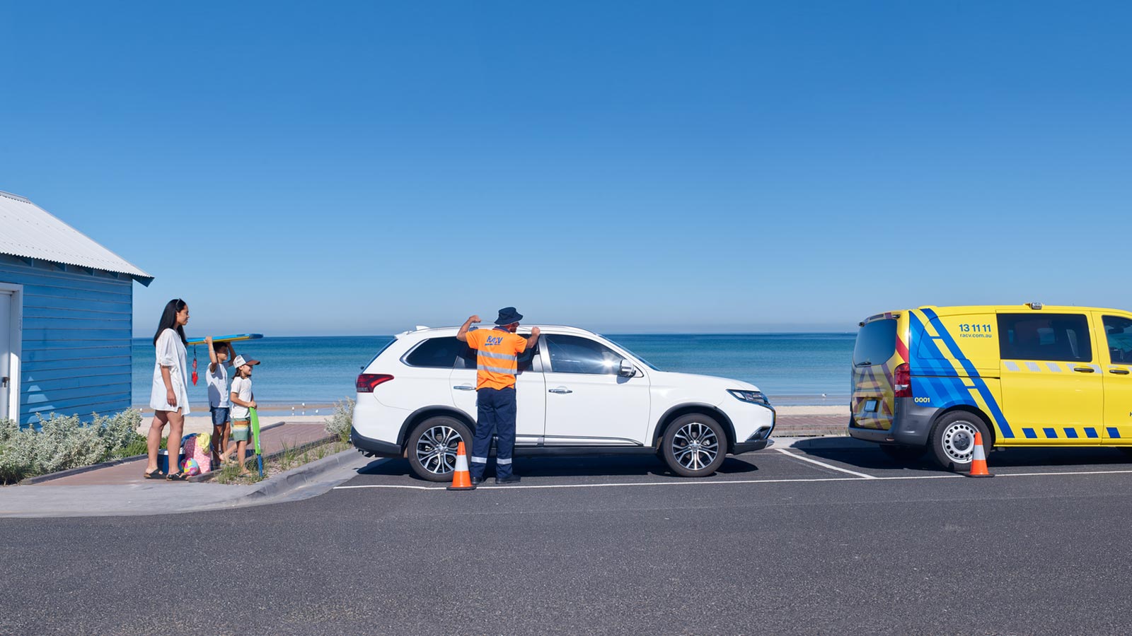 RACV roadside assistance mechanic assessing a family's car at the beach.