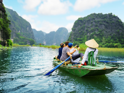 Tourist and a guide riding ina long boat on the water in Vietnam.