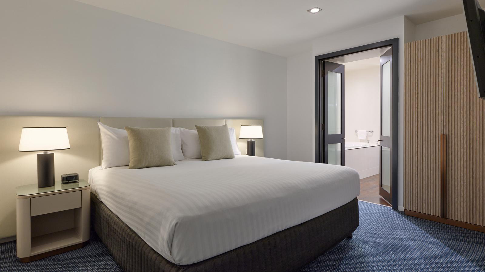 Bed with night stands in deluxe apartment with harbour views at RACV Hobart Resort.
