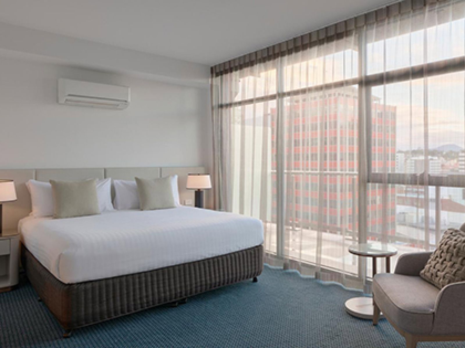 Bed and armchair in bedroom of penthouse at RACV Hobart Resort.