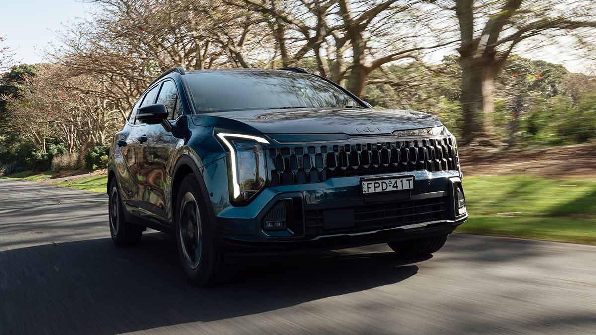 Blue Kia Sportage GT-Line Hybrid on tree-lined country road