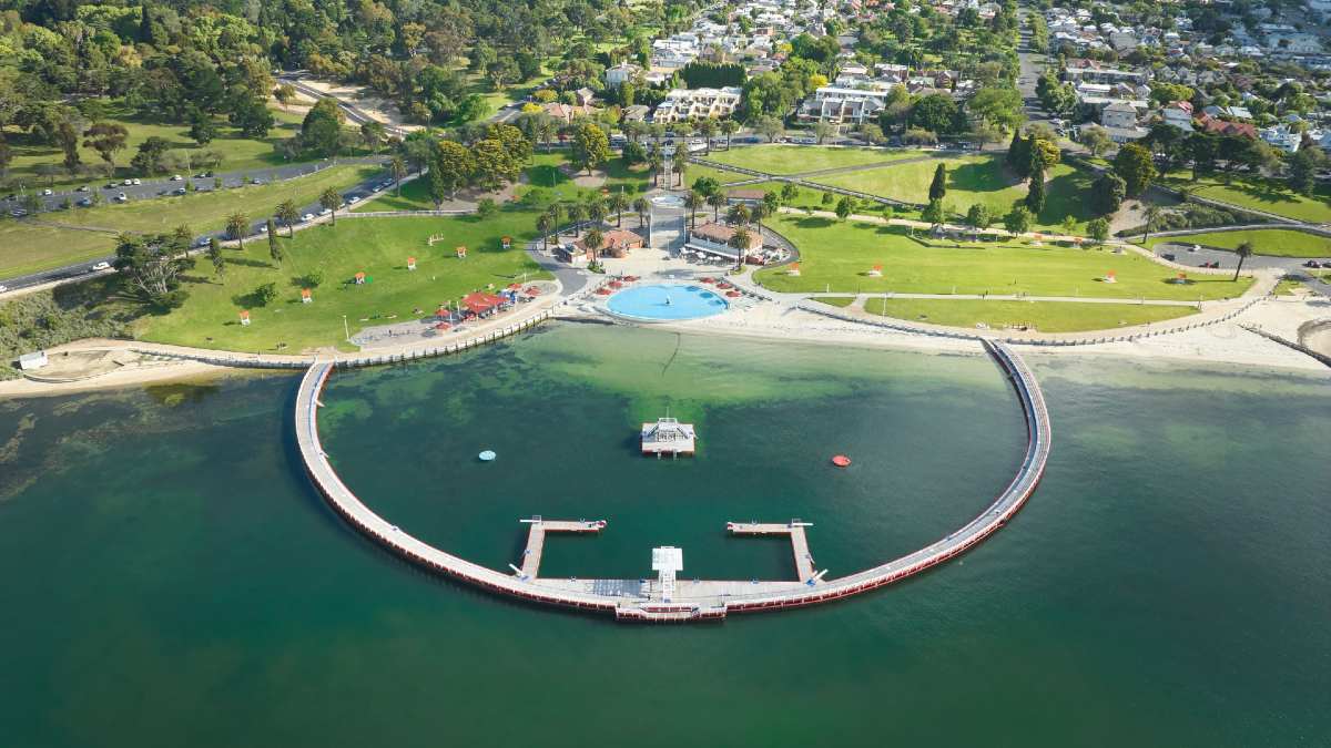 enclosed swimming area in ocean bay with city in background