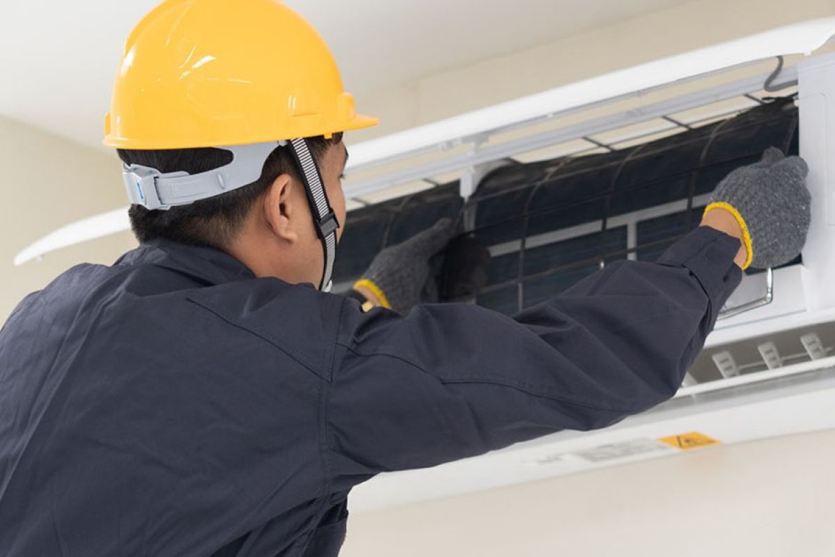 technician cleaning and servicing an air-conditioning unit