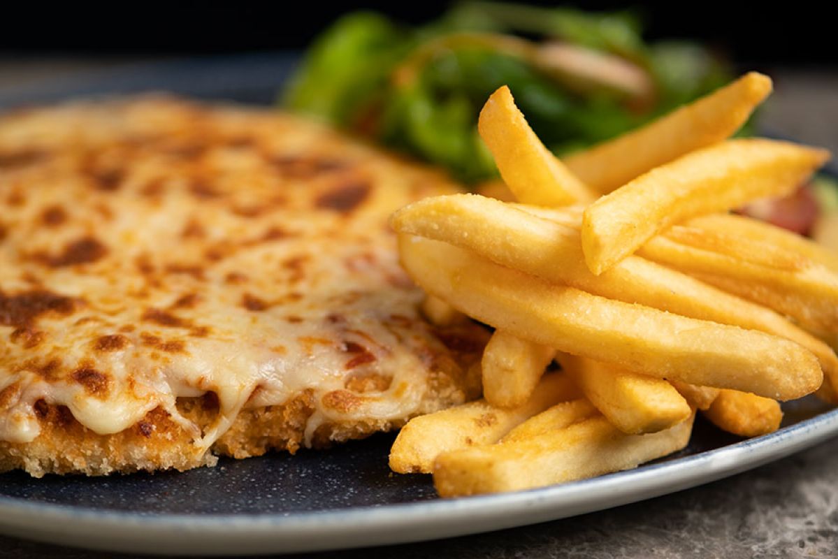 Chicken parma served on a plate with chips and salad