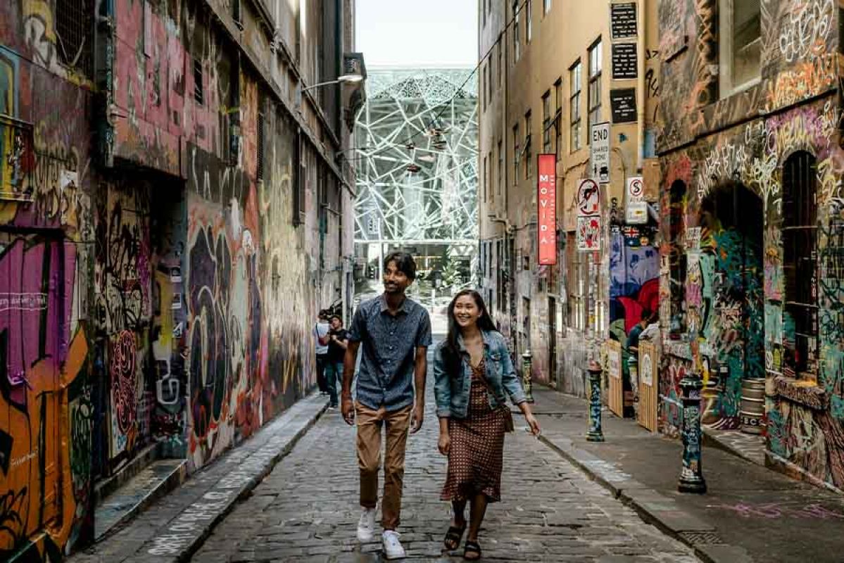 Couple walking down laneway with street art