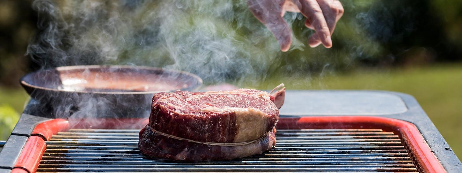 steak being cooked on a grill outdoors