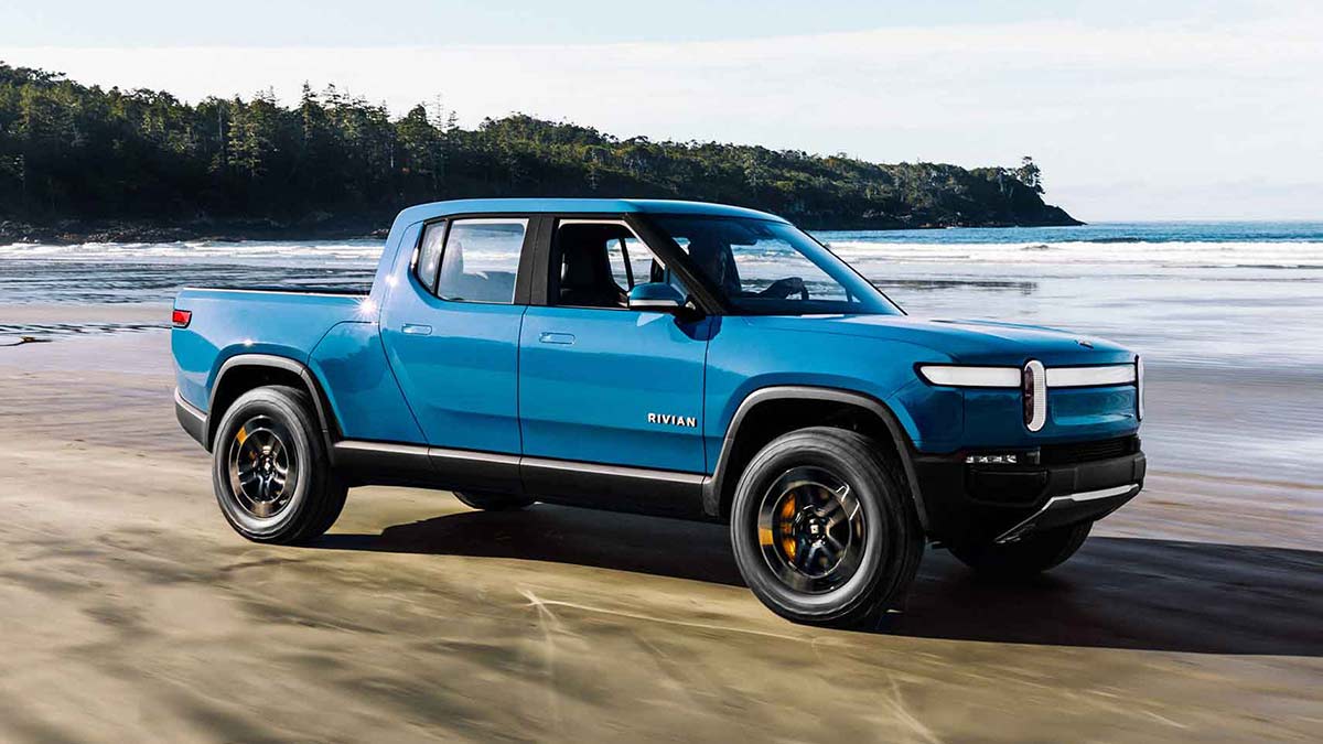 A blue Rivian R1T on a beach