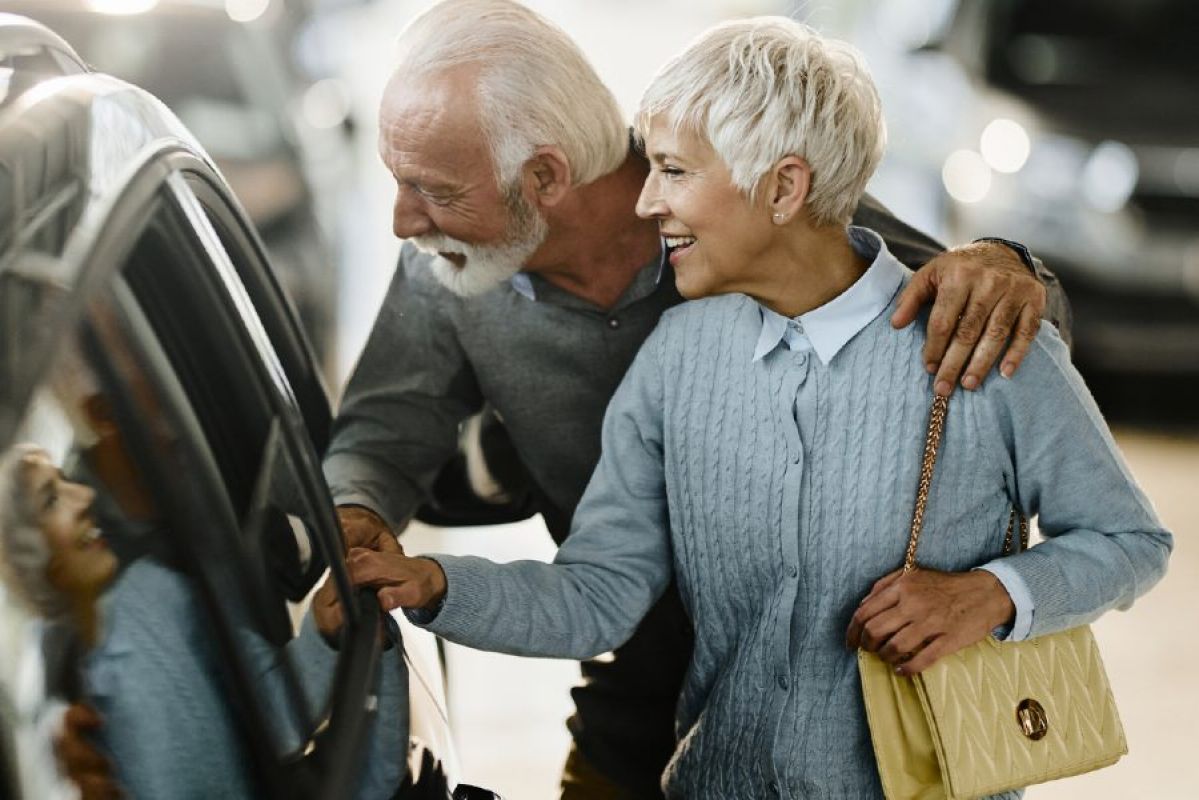An elderly couple inspecting a  car at a dealership