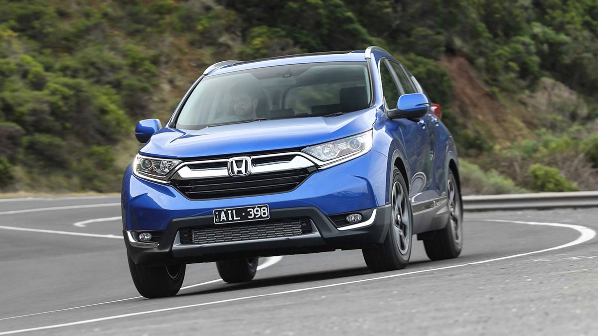 Front side view of a blue Honda CR-V driving on a winding road