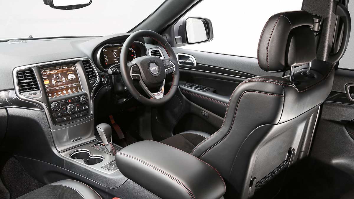 Dark grey interior of the Jeep Grand Cherokee Trailhawk 2018 showing the driver's seat, dashboard and steering wheel