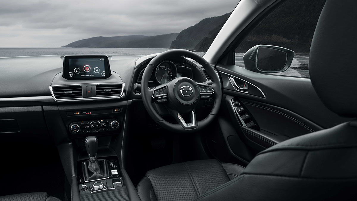 Black interior of the Mazda 3 showing the driver's seat, centre console and steering wheel