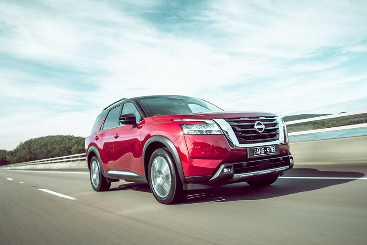 A red Nissan Pathfinder driving on an open highway