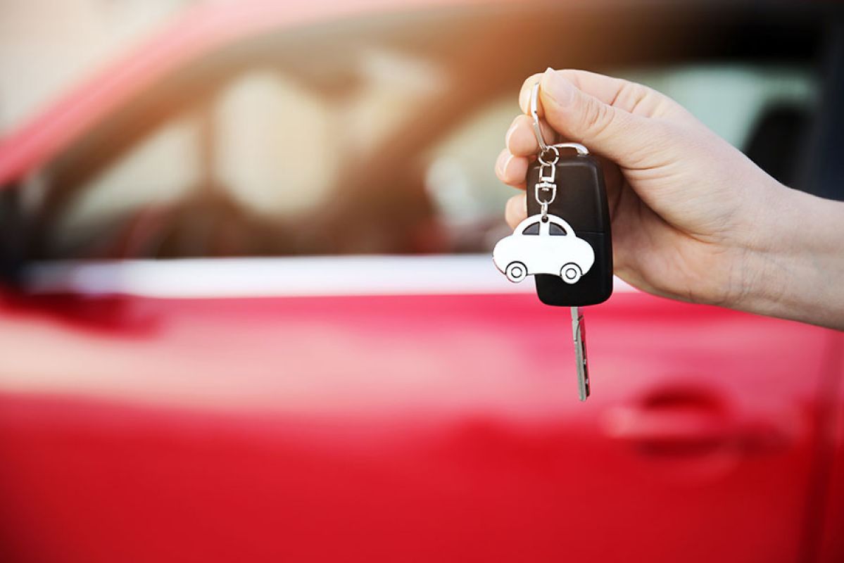 Holding a car key in front of a used car