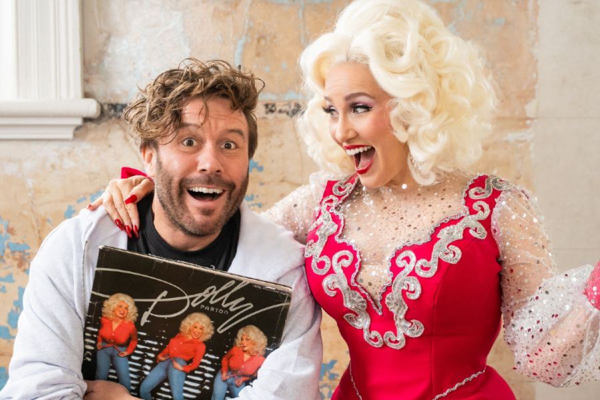 young man holding a Dolly Parton record being hugged by Dolly