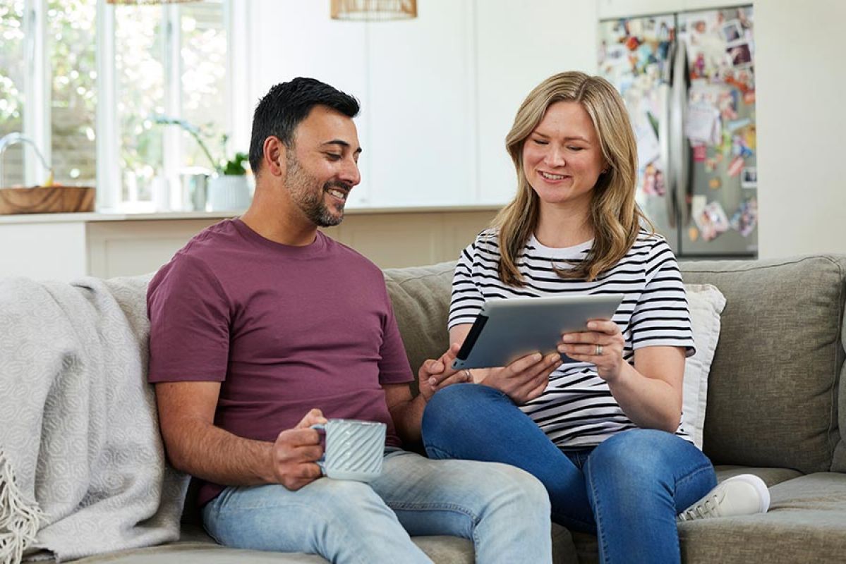 Man and woman on couch looking at computer tablet