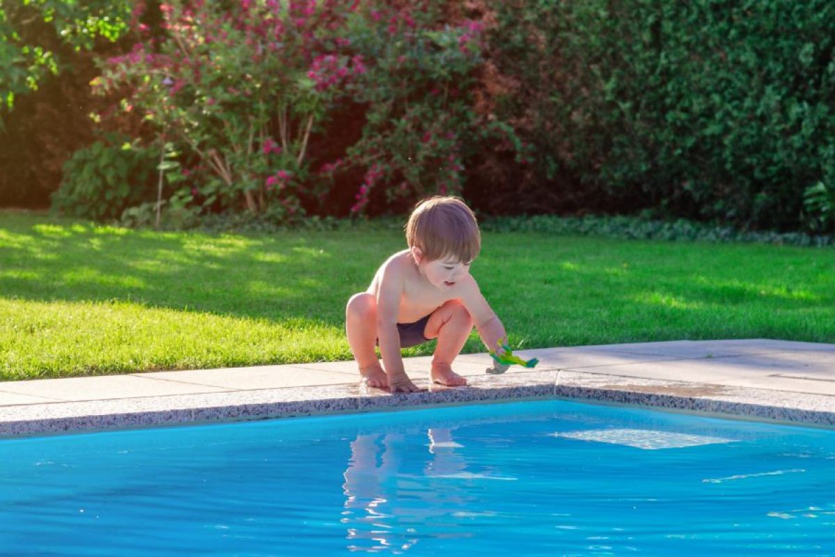 small boy leaning over swimming pool