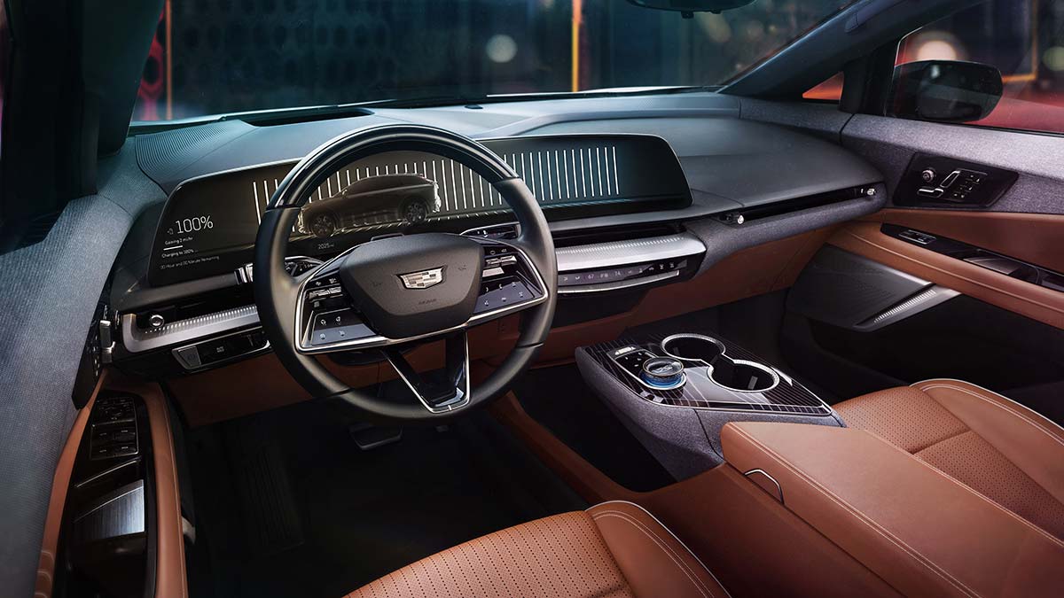 Dark interior of Cadillac Optiq SUV with large curved dash and tan-coloured seat and door trim