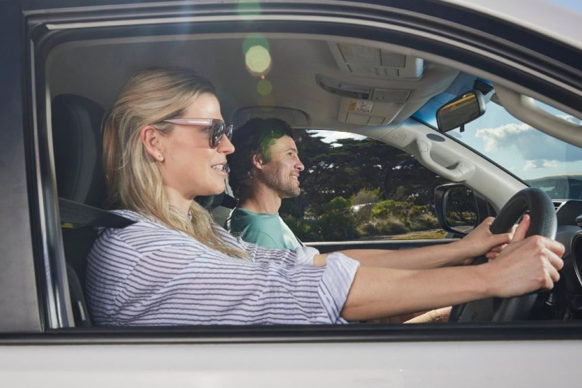 A woman driving a car with a man in the front passenger seat