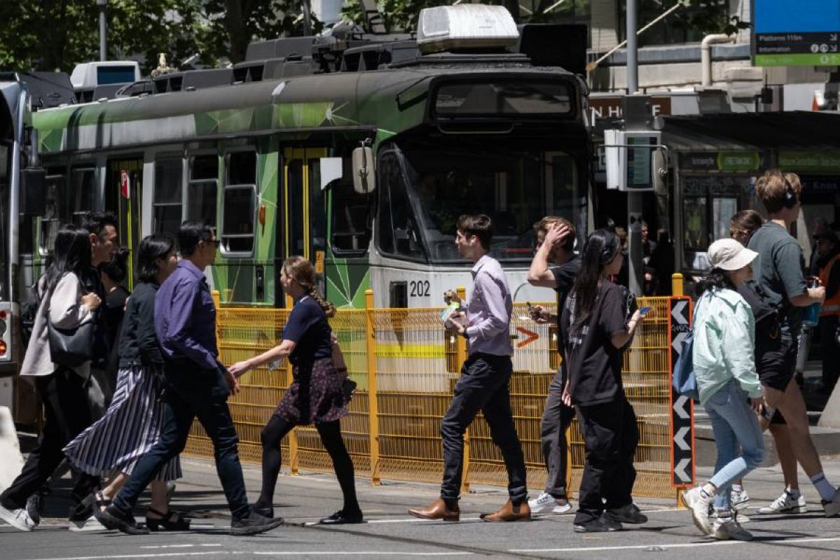 Pedestrians walking in front of a tram near Melbourne Central Station