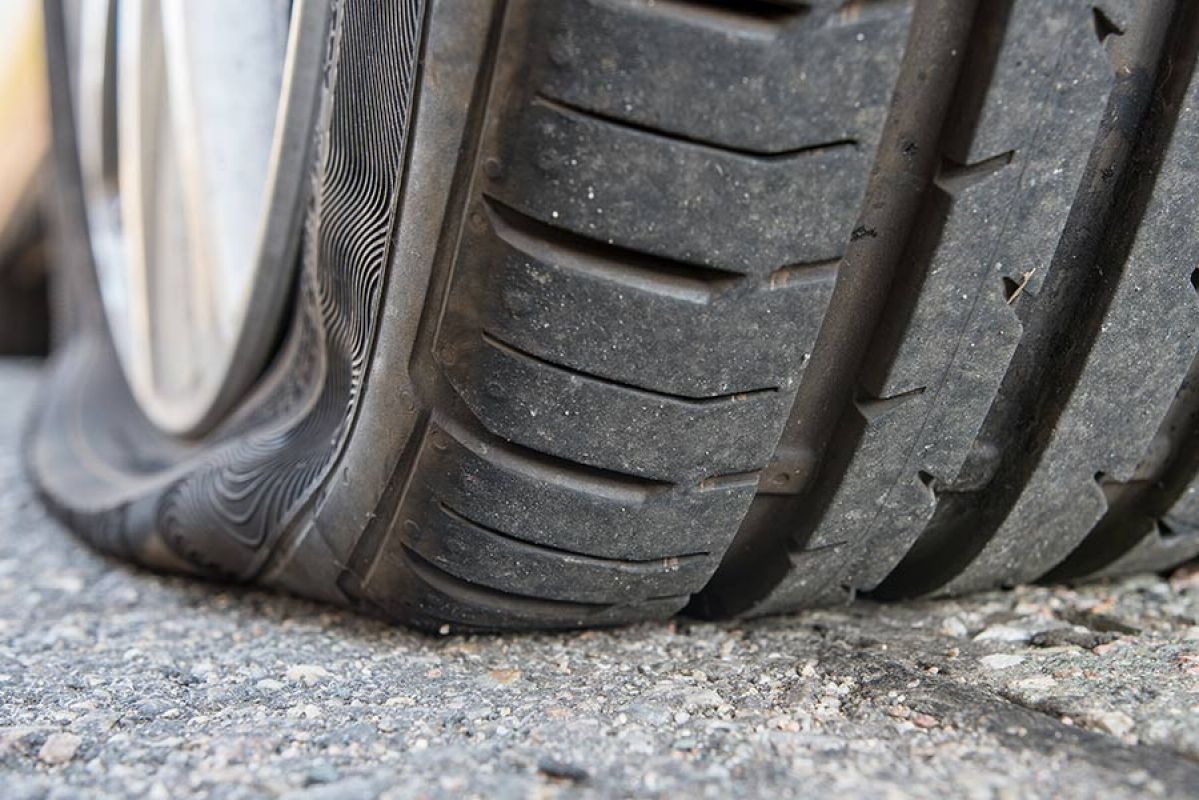 Close-up of flat tyre on back wheel of car on paved surface