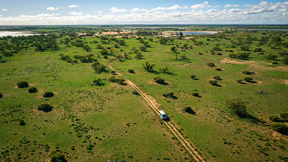 Aerial view of van on remote track with sparse, sandy terrain near Murray River, Mildura region