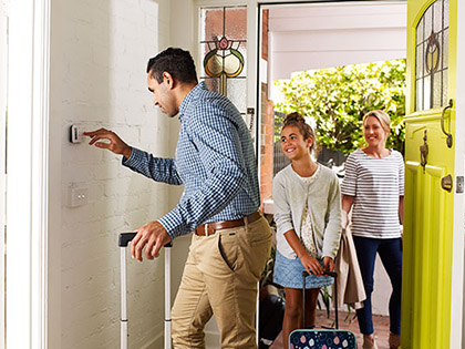 Family entering their home and the father types a code into the home security system.