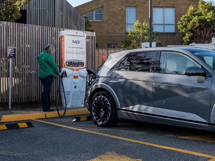 Person charging an electric vehicle at an RACV EV charging station.