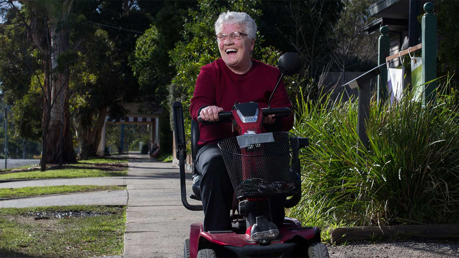 Elderly person smiling while using their mobility device.