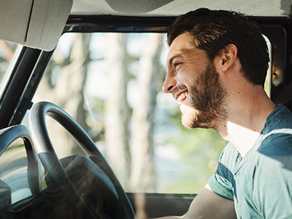 Man smiling while sitting in his car.