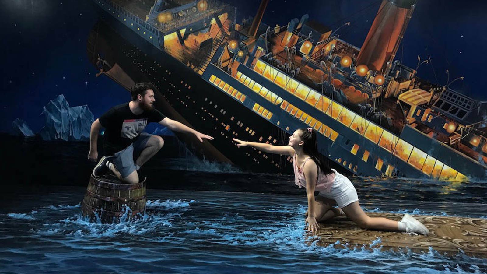 Couple posing in front of 3D artwork at ArtVo, depicting the Titanic sinking.