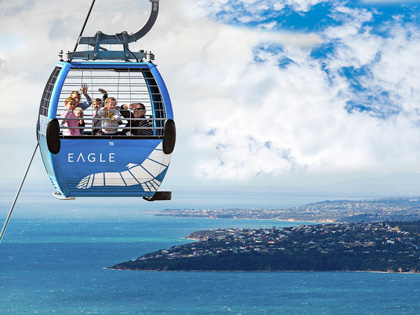 A family riding in the Eagle of Arthurs Seat with a view of the coast.