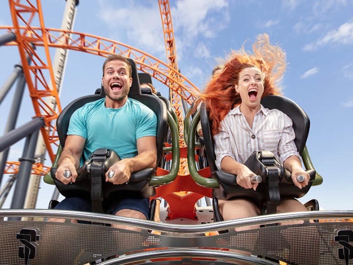 Man and woman riding orange roller coaster at Dreamworld.