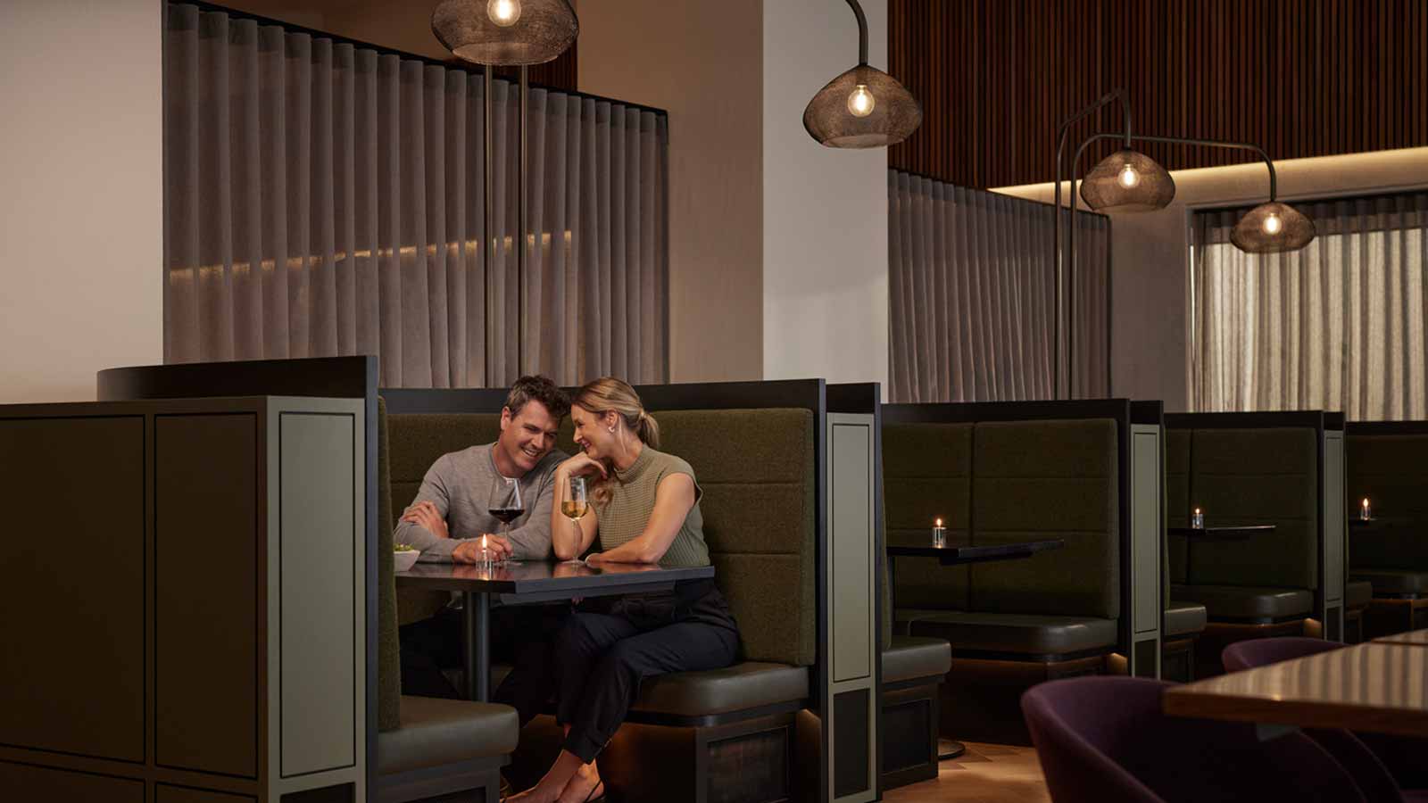 A couple sitting in a booth at Banyalla restaurant drinking wine. 