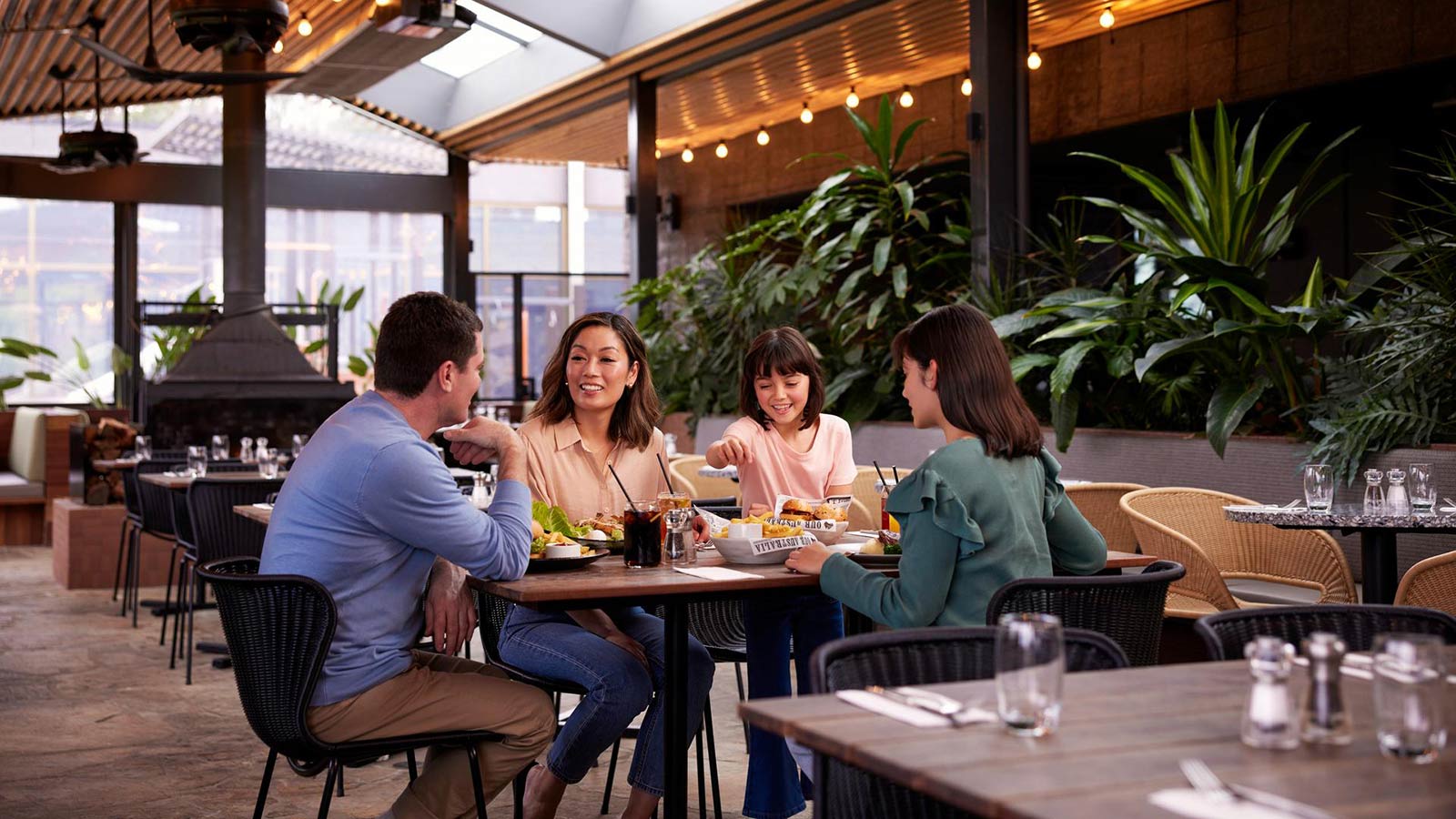 Parents and two children smiling together and eating at the Riddell's Green restaurant at RACV Healesville Country Club & Resort.