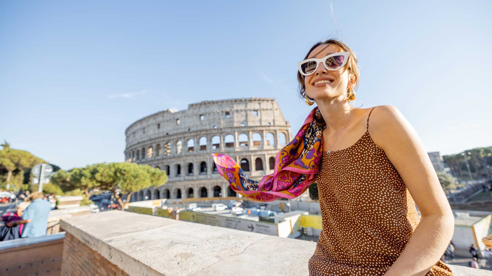 Portrait of a cheerful woman on background of Coliseum in Rome on a summer time. 