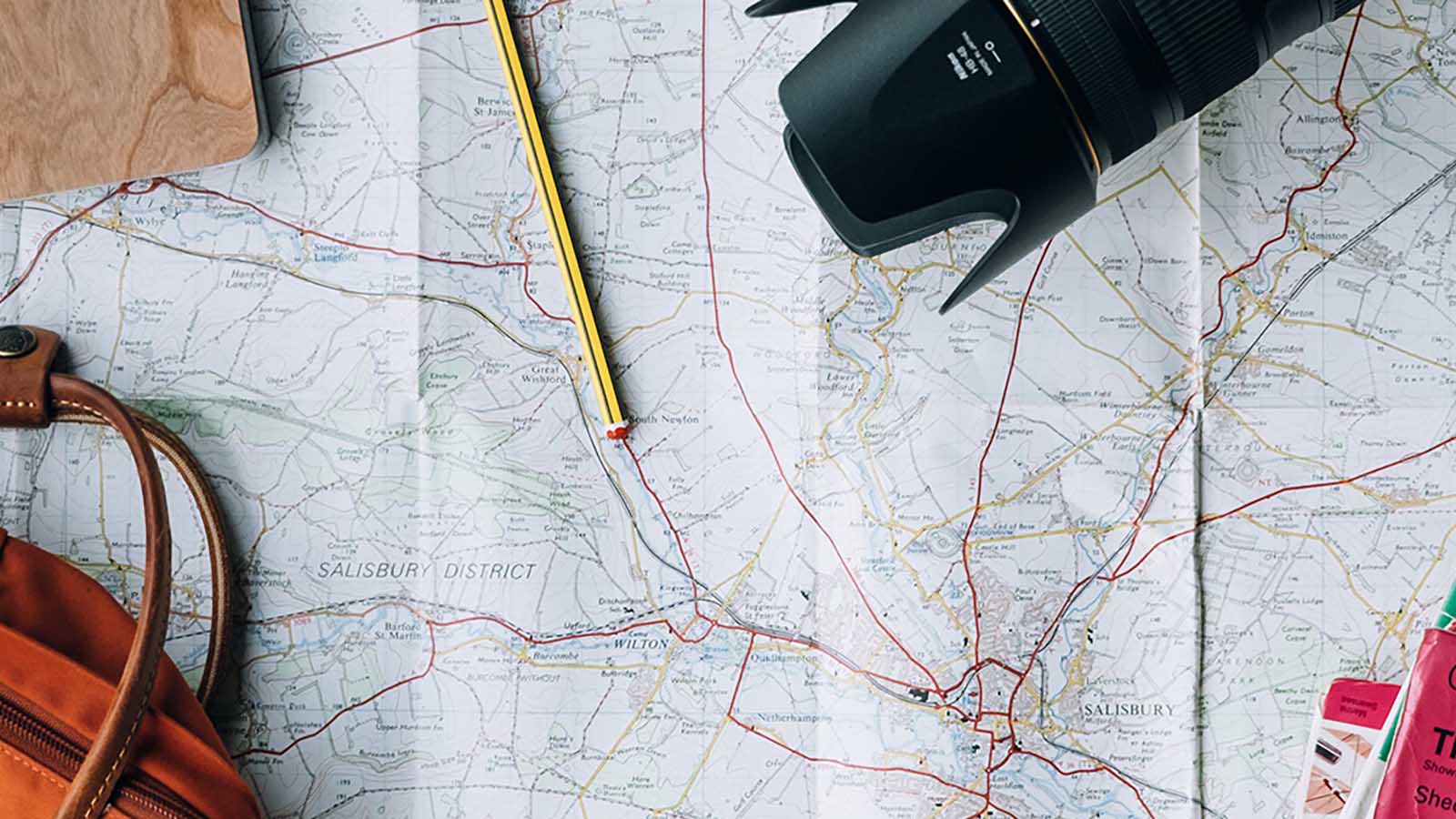 Image of camera and pencils on top of paper map.