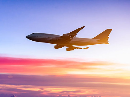 Plane in the sky at sunset.