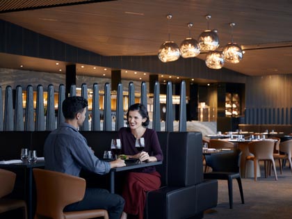 A couple at the Cape Shanck restaurant, smiling at each other while holding two glasses of red wine. 