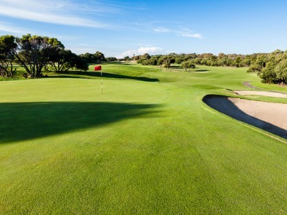 The sunlit vista of the golf course at RACV Cape Schanck Resort, with a green on the left and a sand trap on the right