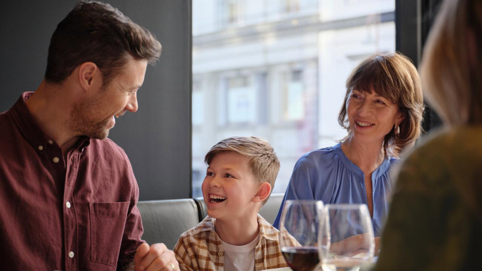 Family laughing and eating dinner together at RACV Hobart Hotel's Charcoal restaurant.