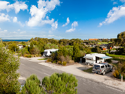 Cars parked RACV Inverloch Resort's caravan site, surrounded by greenery.