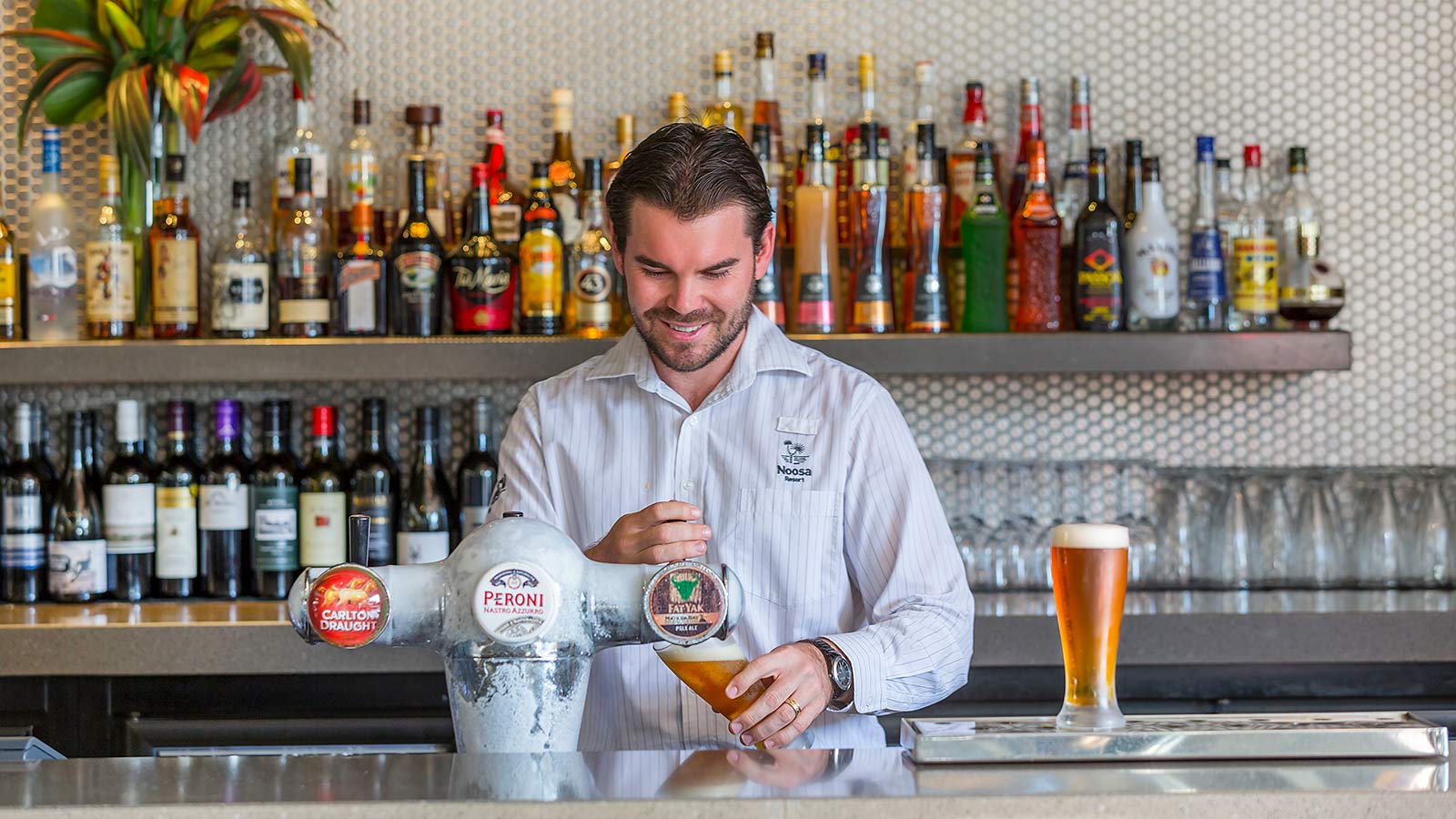 Bartender at Dazza's Bar at RACV Noosa Resort preparing drinks.