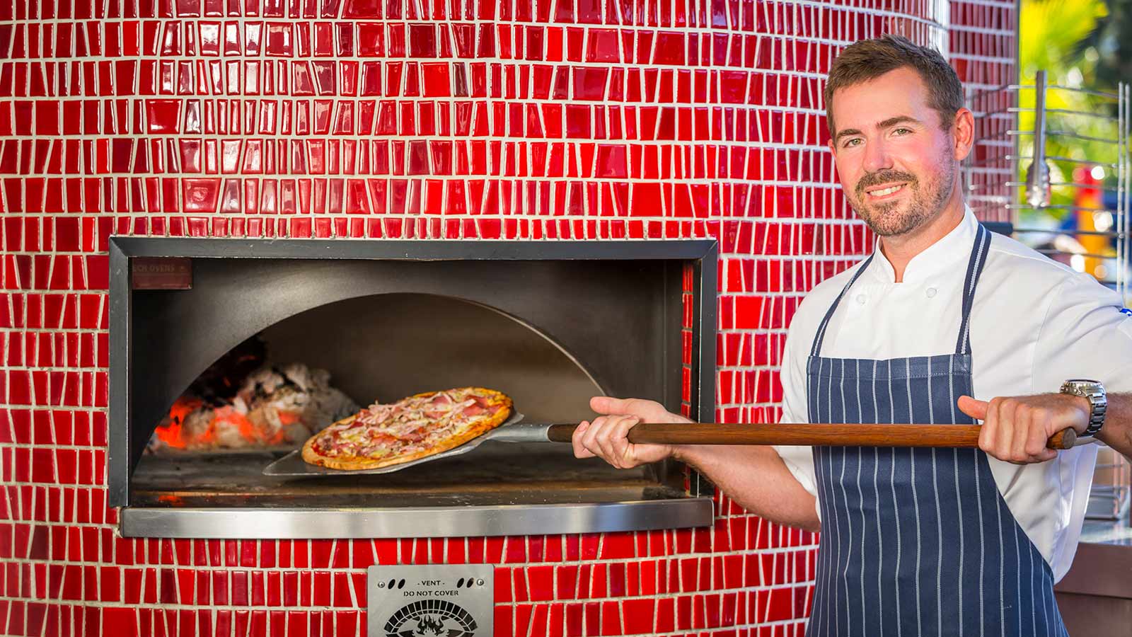 Chef taking a pizza out of the wood-fire oven at Dazza's Bar at RACV Noosa Resort.