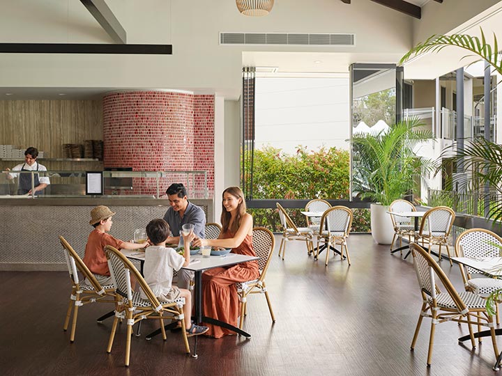 Parents and two children sitting and eating together at Dazza's Bar at RACV Noosa Resort.