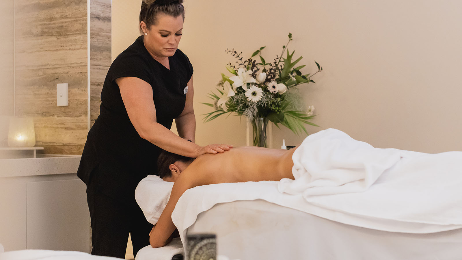 Person laying on the stomach receiving a massage from a massage therapist at RACV Noosa Resort's One Spa.