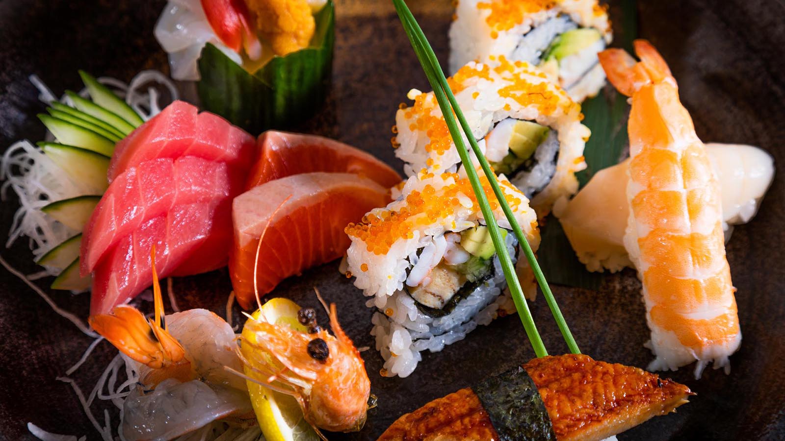 Plate featuring a variety of sashimi, sushi rolls and nigiri.