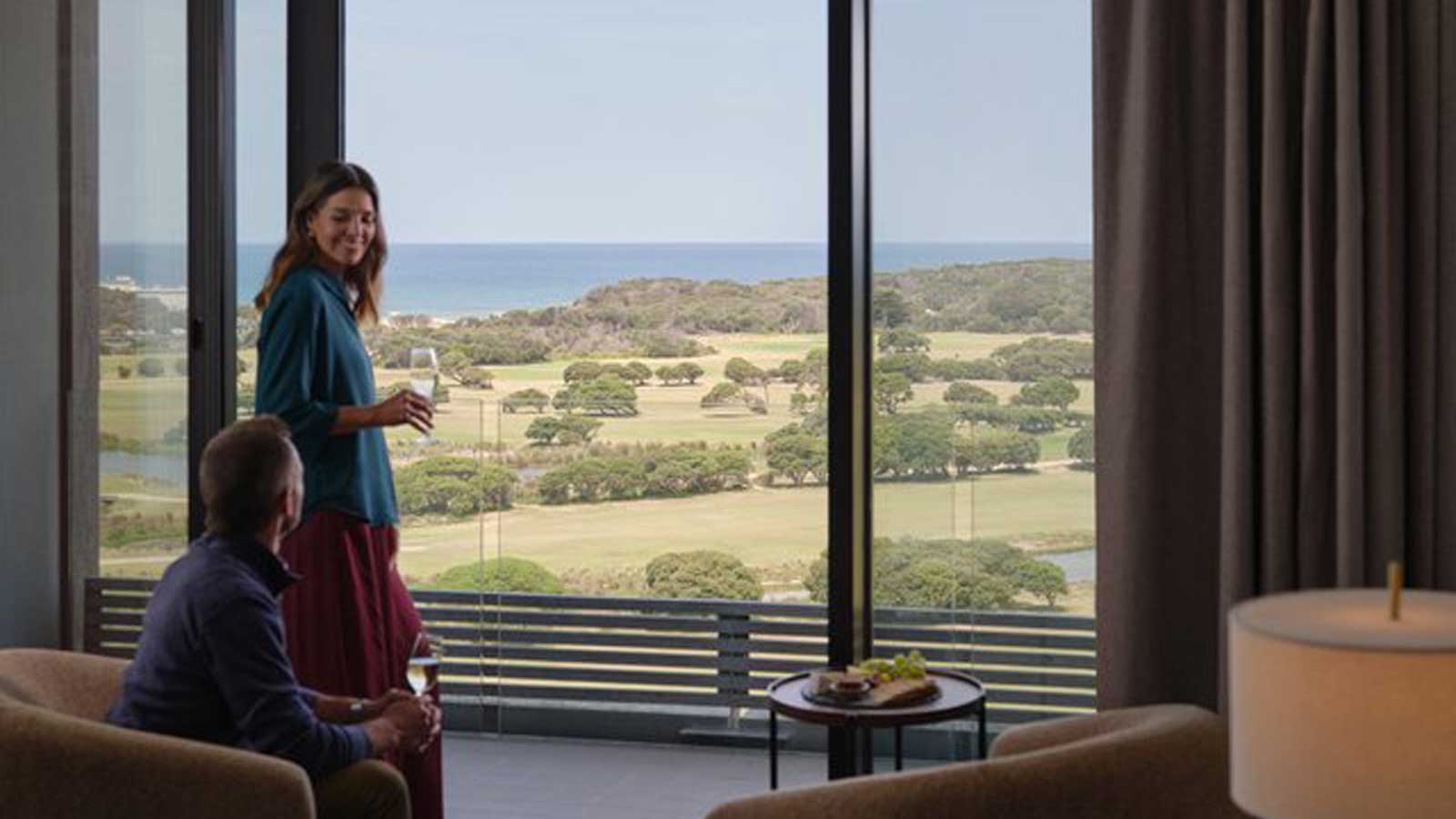 A couple enjoying a glass of wine with the view from a premium mountain room at RACV Healesville.