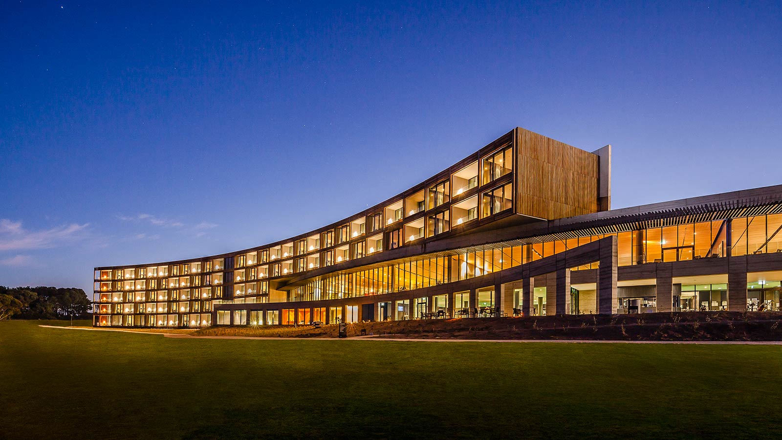 Exterior of RACV Torquay Resort, lit up in the evening.